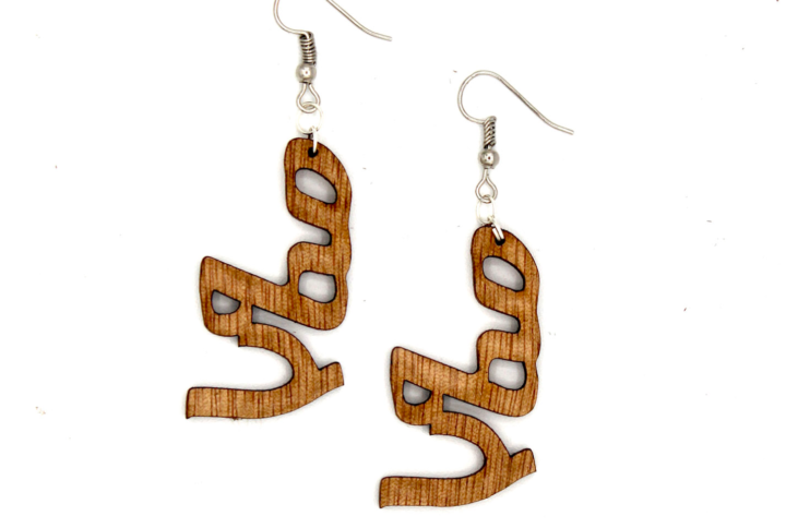 Natural wooden earrings featuring the Ge’ez inscription ‘Mela,’ meaning purpose — hand-carved with heritage detail.