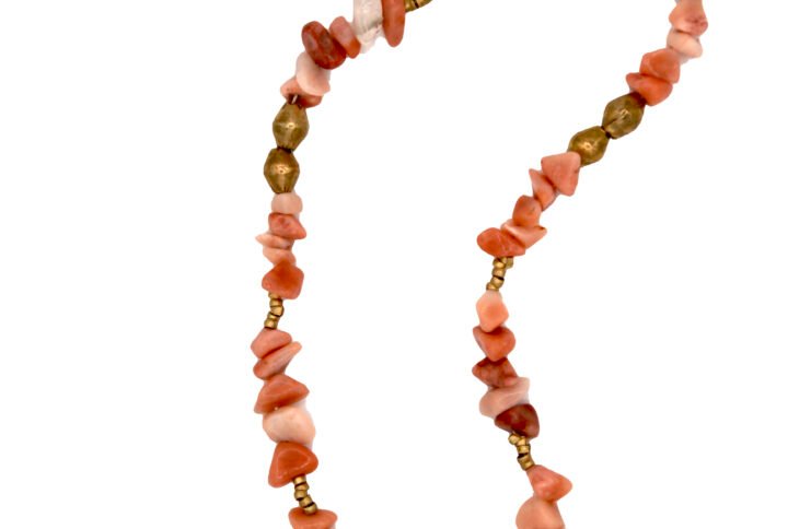 Handcrafted Ethiopian necklace with soft peach beads and gold-toned amulet accents.